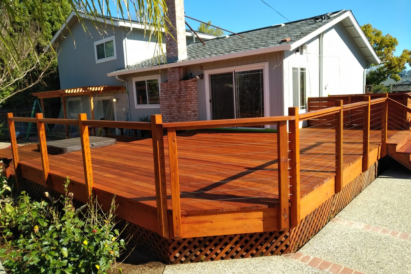 Wood deck with cable railing and lattice skirting behind a house