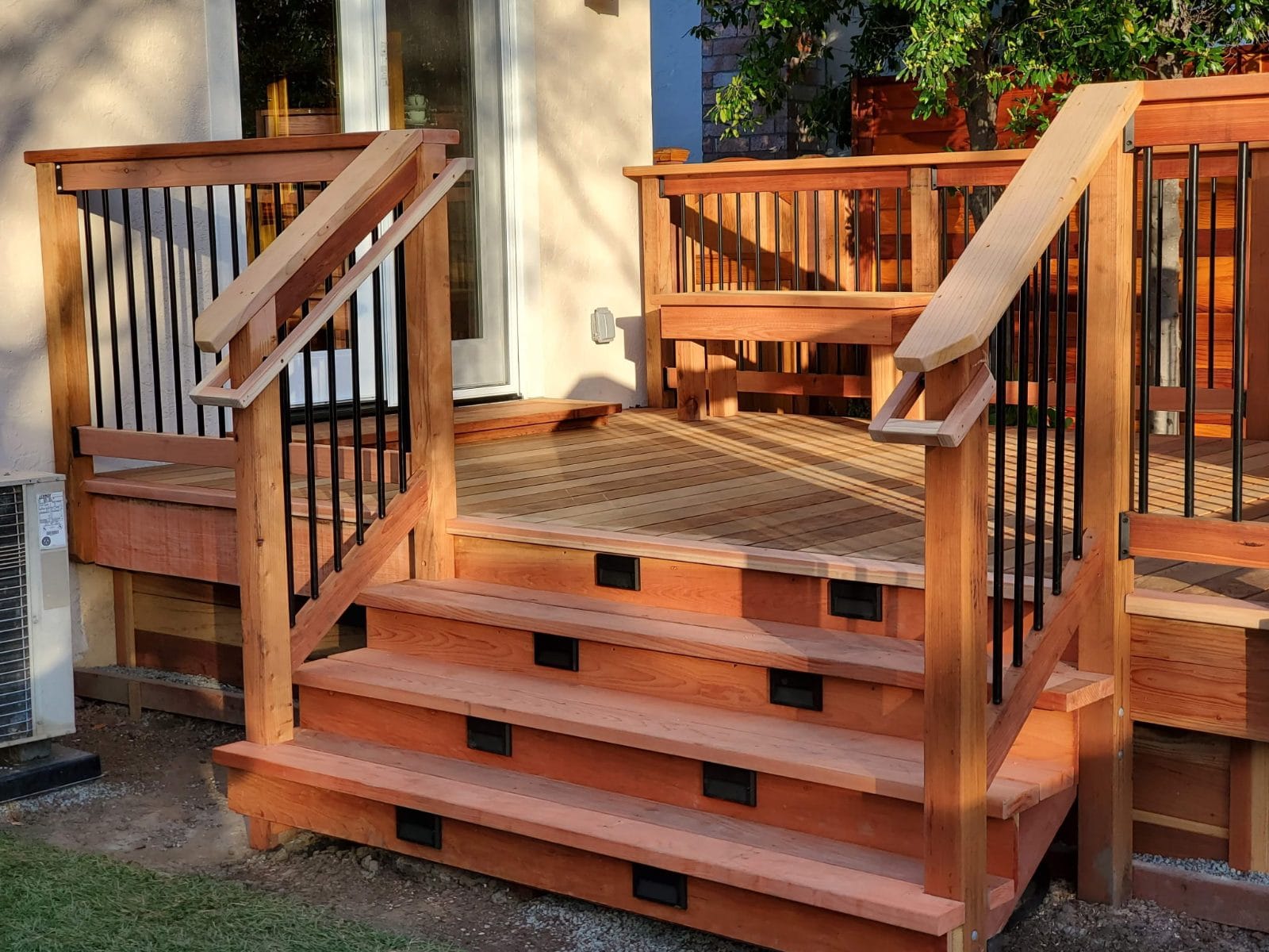 Wood deck stairs with black metal balusters and step lights