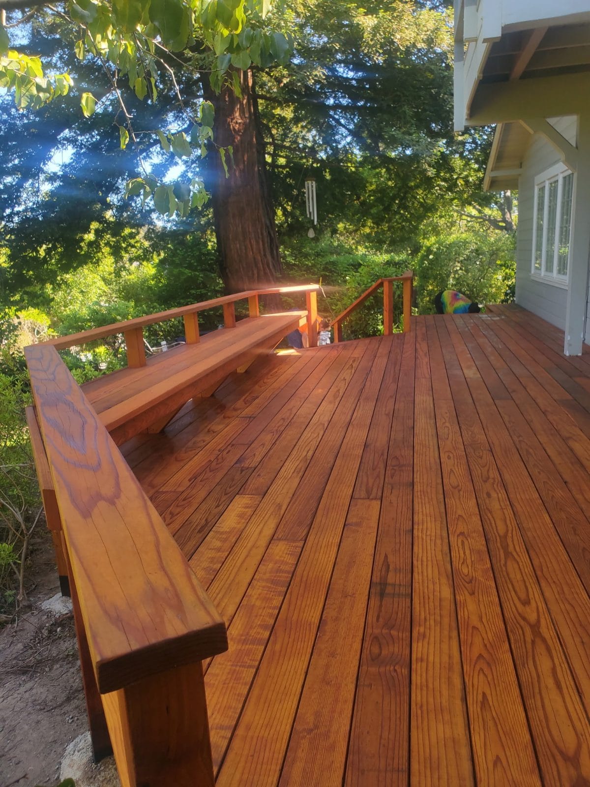 Wood deck with a built-in bench under tall trees