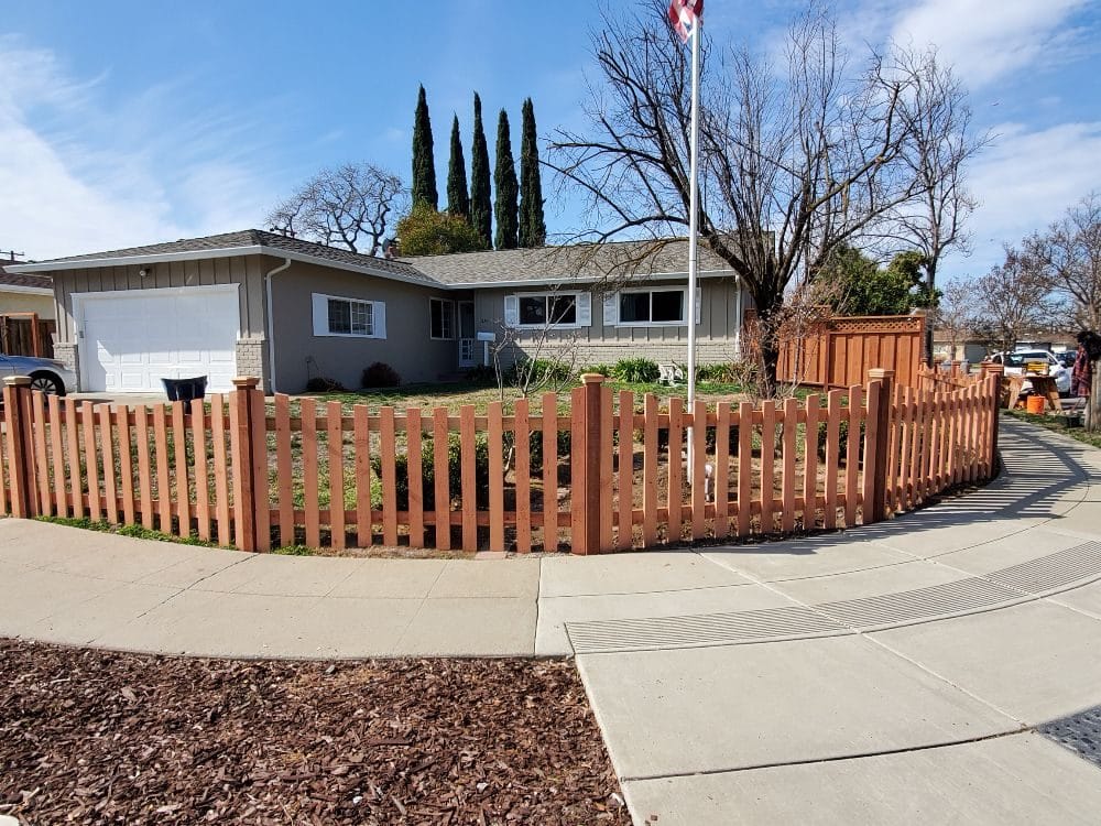 Redwood swoop-top picket fence along a driveway